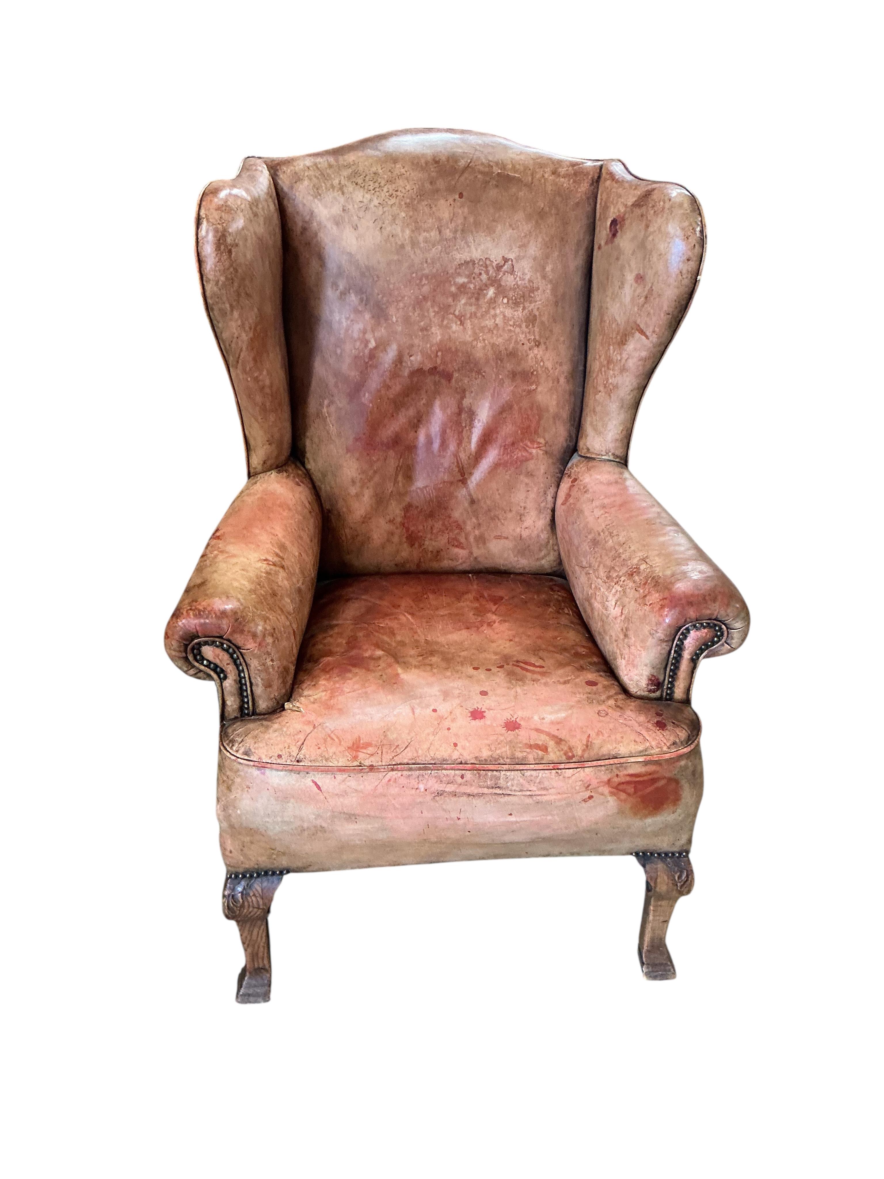 A George III style studded pale red leather wing armchair on carved oak cabriole legs, width 74cm, depth 78cm, height 110cm